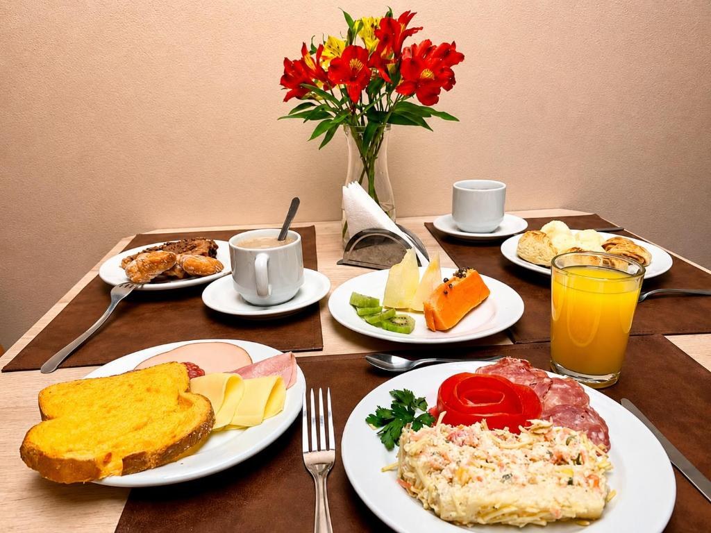 Mesa do café da manhã da Pousada Bello Outono, com frios, frutas, pães, suco e café